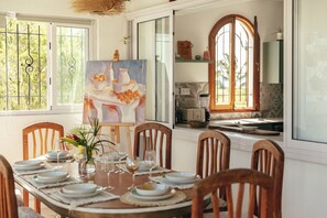 A dining area with a table set for six, surrounded by wooden chairs.