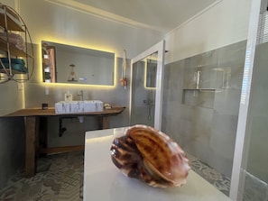 A bathroom with a vanity, mirror, sink, and shower.