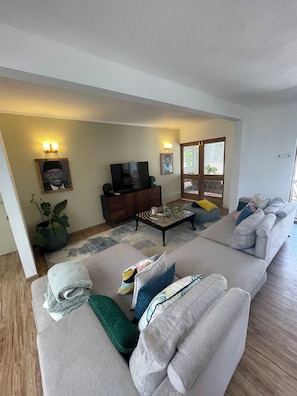 A living room with a sofa set, a coffee table, a TV, and wall-mounted lights.