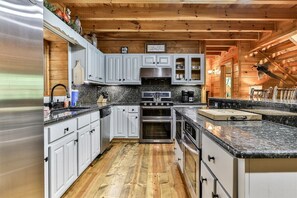 Eine moderne Küche mit weißen Schränken, Granit Arbeitsplatten, Edelstahlgeräten und einer Holzbalkendecke.