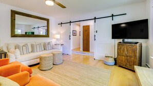 A living room with a sofa, ottoman, and a television on a wooden cabinet. - Wine Country Retreat in Russian River Valley! (Forestville)