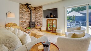 A cozy living room with a brick fireplace, comfortable seating, and a large sliding glass door leading to an outdoor patio. - Wine Country Retreat in Russian River Valley! (Forestville)