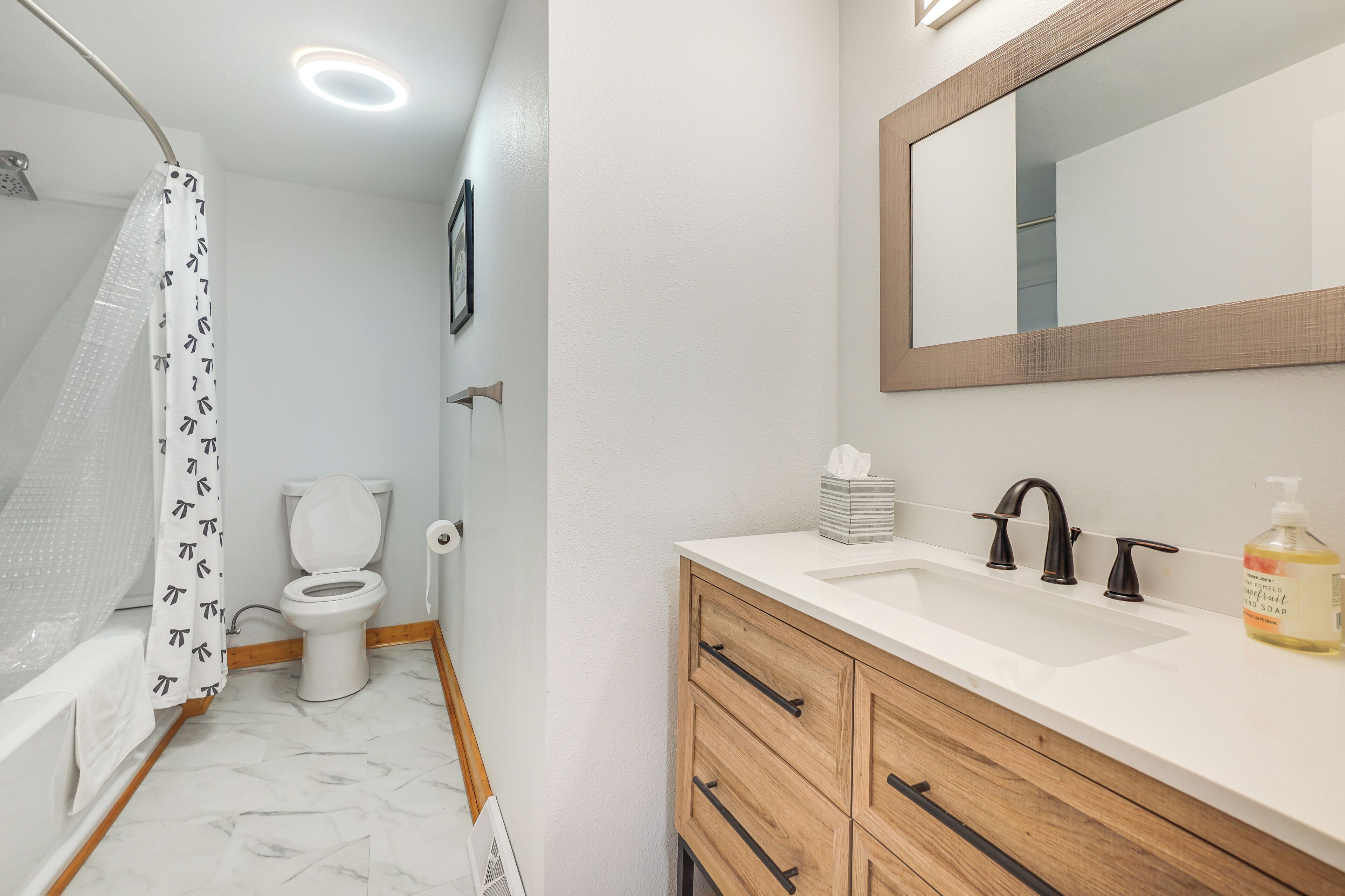 A bathroom with a shower, toilet, sink, and wooden cabinets.