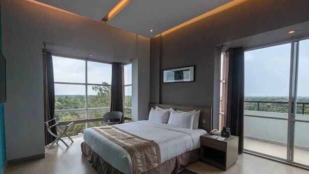 Une chambre d’hôtel moderne avec un grand lit, une table de chevet, une chaise et un balcon avec vue.