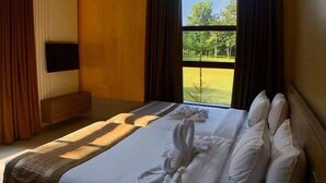 Une chambre d’hôtel avec un grand lit, un téléviseur à écran plat fixé au mur et une fenêtre avec des rideaux.