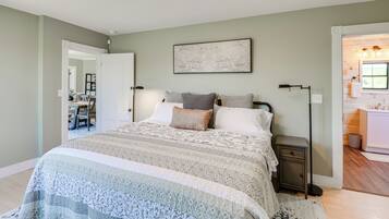 A bedroom with a large bed, bedside tables, a floor lamp, and a painting on the wall.