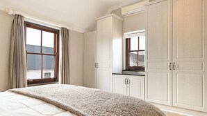 A bedroom with a large bed, a window with curtains, and a wardrobe. - Winelands Golf Lodges 10 (Cape Town)