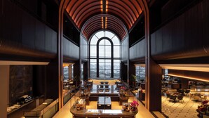 A spacious lobby with a high arched ceiling, large windows, and a central seating area.