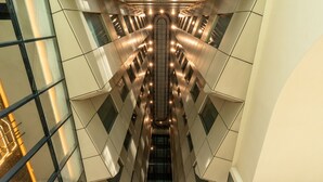 A modern interior with a central staircase and glass railings.
