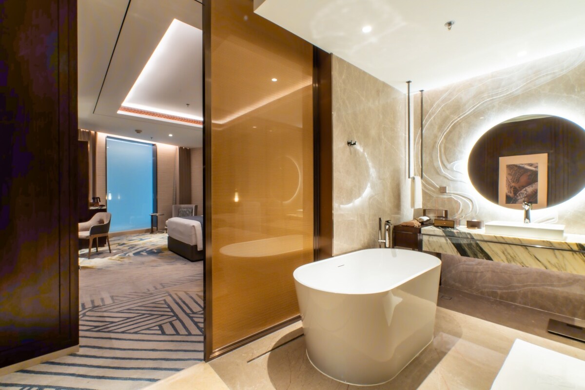 A modern bathroom with a freestanding bathtub, a marble countertop, and a large mirror.