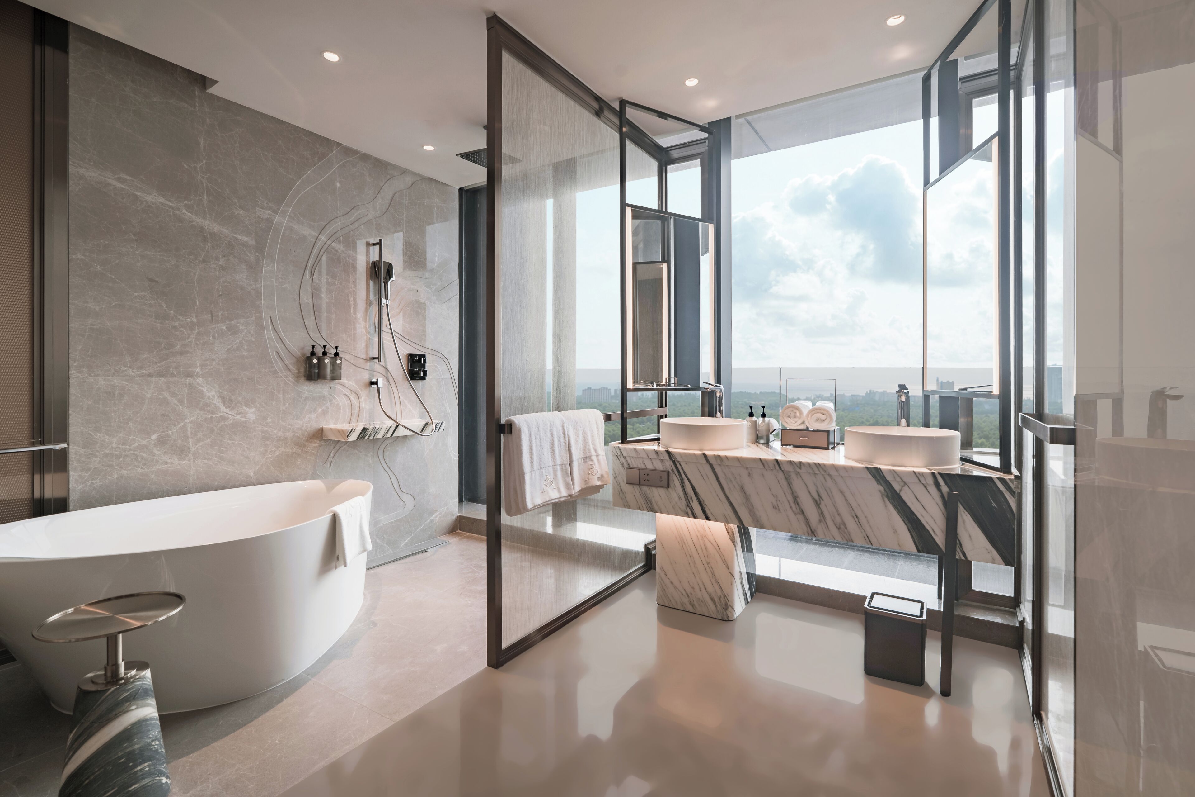 Une salle de bain moderne avec une baignoire sur pieds, un grand miroir et un meuble-lavabo doté d’un plan de travail en marbre.