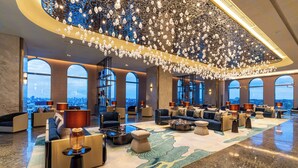 A spacious lobby with modern seating, large windows, and a decorative ceiling.