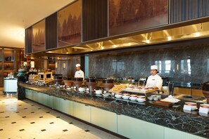 Tilava buffet-alue, jossa on marmoritasot, useita ruokailupisteitä ja kokkeja valmistamassa ruokaa.