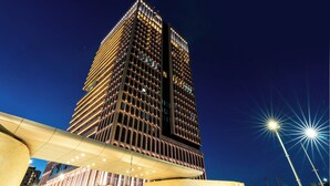 A high-rise building with a modern architectural design, featuring a grid of windows and a prominent vertical structure.