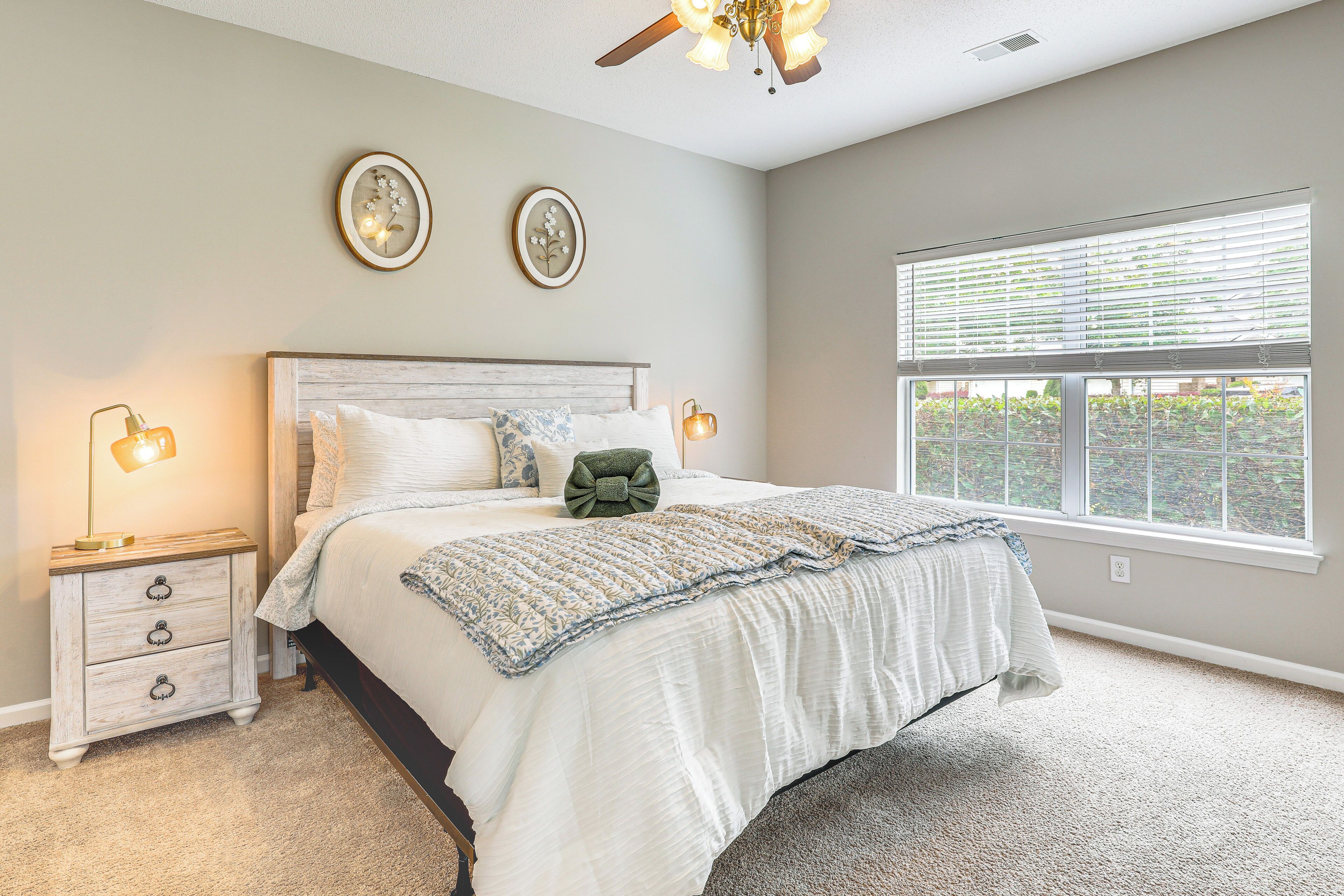 A bedroom with a bed, bedside tables, and a window with blinds.