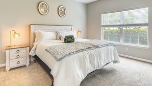 A bedroom with a bed, bedside tables, and a window with blinds.
