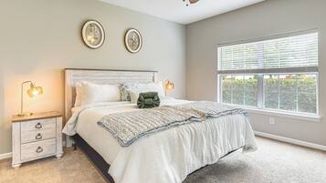 A bedroom with a bed, bedside tables, and a window with blinds.