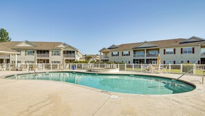 A swimming pool surrounded by a wooden fence, with a clear blue sky above.