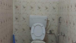 Een kleine badkamer met toilet, douche en betegelde wanden.