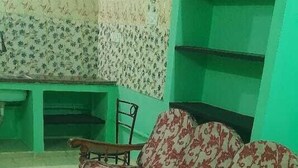 Een kamer met een groene wand, een gestreept bankstel, een stoel en een betegelde vloer.