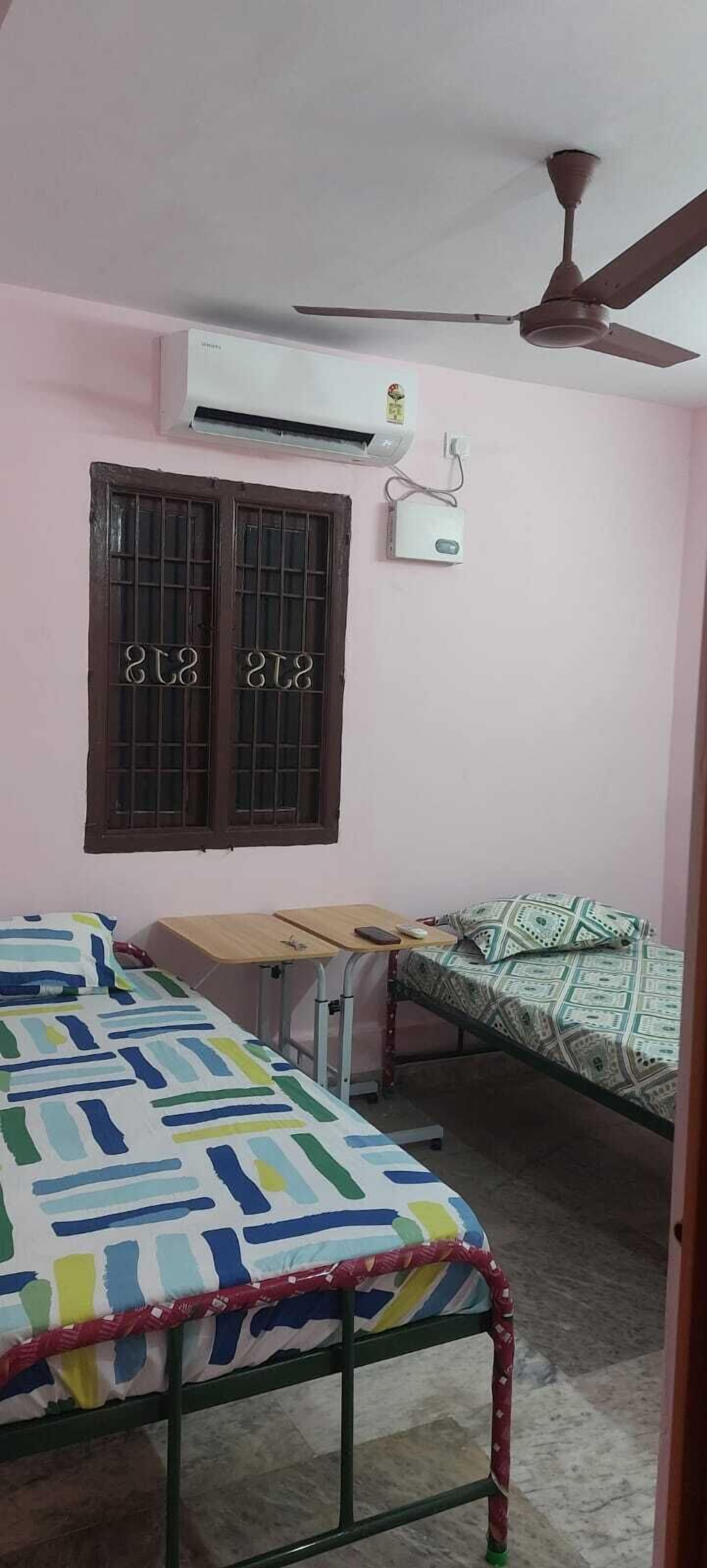 Une chambre avec deux lits, un ventilateur de plafond, un appareil de climatisation et une fenêtre portant un numéro.