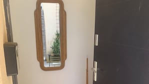A room with a wooden bench, a mirror on the wall, and a broom leaning against the wall. - Room "Abricot (Uzès)