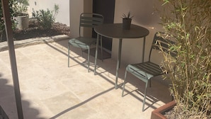 An outdoor patio with a table and chairs, a potted plant, and a bucket. - Room "Abricot (Uzès)