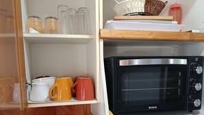 Una cocina equipada con microondas, hervidor y diferentes utensilios.