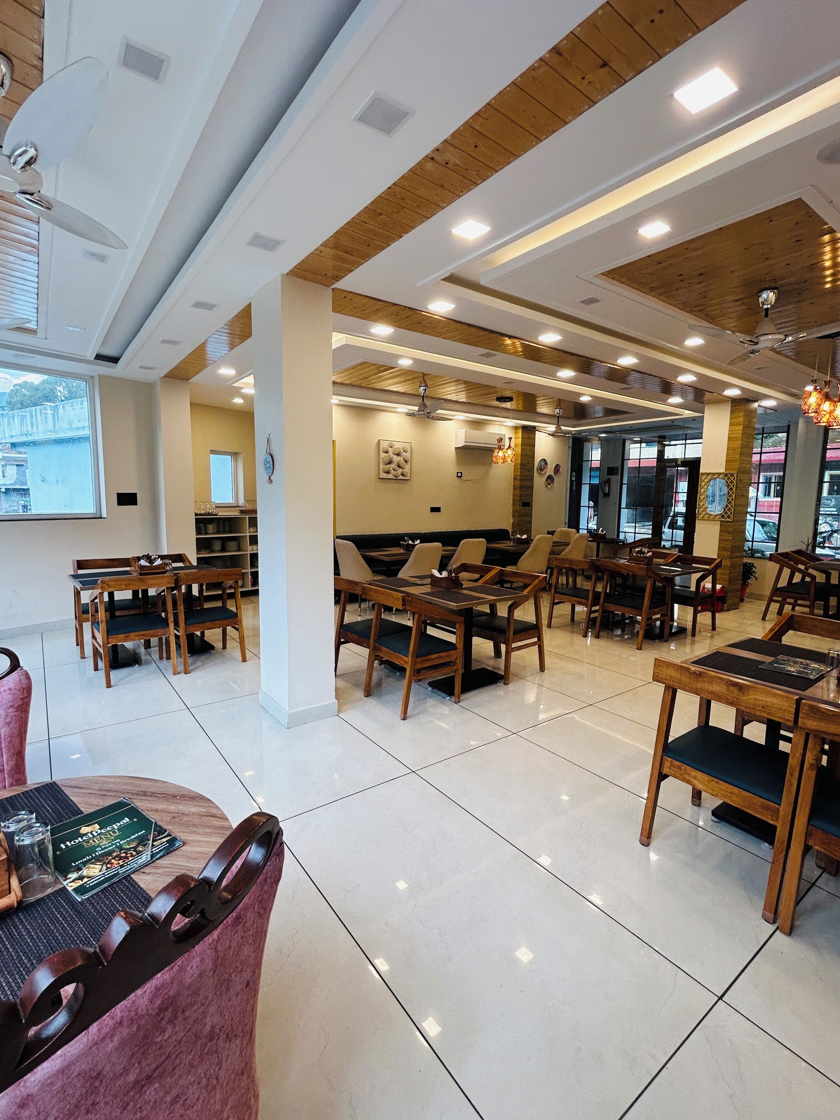 A restaurant with wooden tables and chairs, a tiled floor, and a view of the outside.