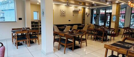 A restaurant with wooden tables and chairs, a tiled floor, and a view of the outside.