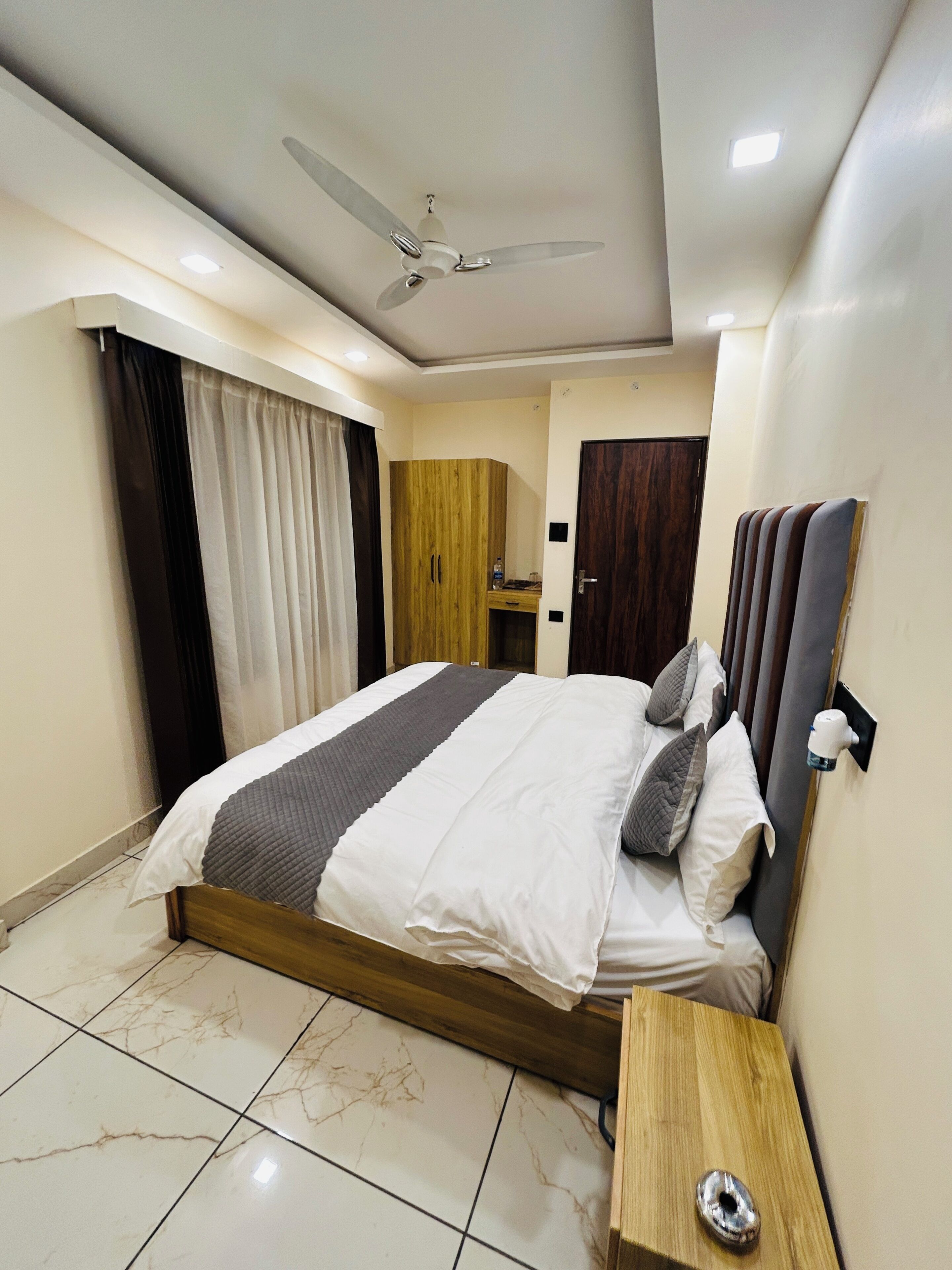 Un dormitorio con cama, mesita de noche, armario, ventilador de techo y una puerta.