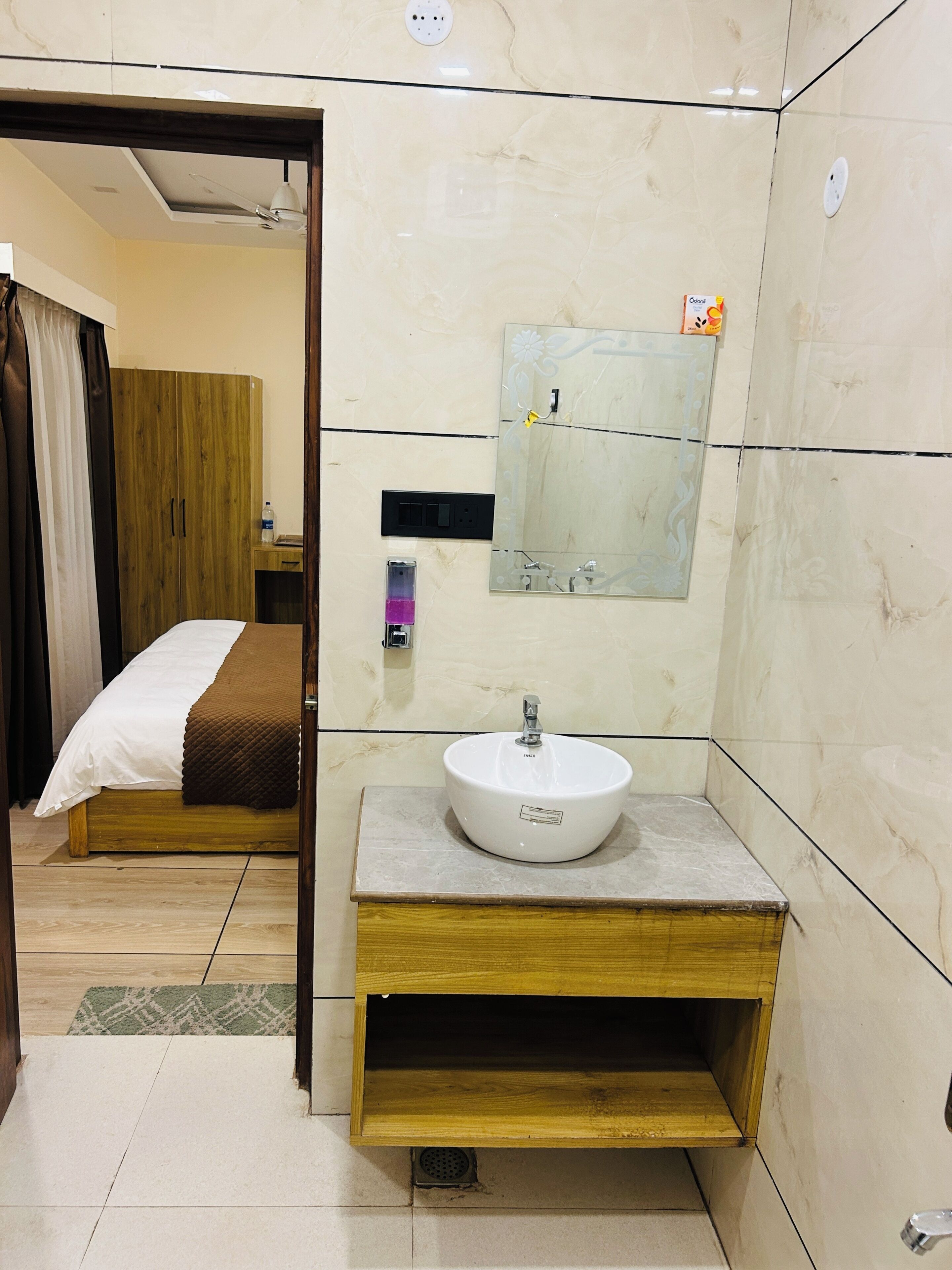 A hotel room with a wooden bed, a white sink, a mirror, and a wardrobe.