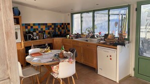 A kitchen with a tiled backsplash, wooden cabinets, a white refrigerator, and a dining area with a table and chairs. - House near Montpellier quiet and bright swimming pool (Laverune)