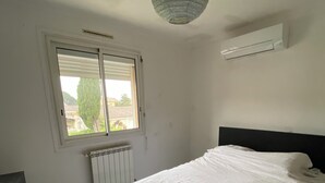 A bedroom with a bed, a radiator, a window, and an air conditioning unit. - House near Montpellier quiet and bright swimming pool (Laverune)