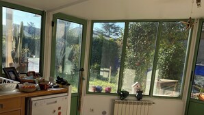 A kitchen with a dining table, a dishwasher, and a window with a view of greenery. - House near Montpellier quiet and bright swimming pool (Laverune)