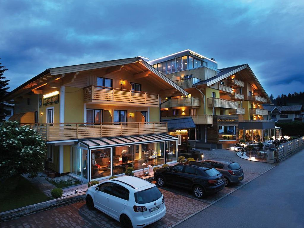 Un hotel de varios pisos con balcones, un restaurante y una zona de estacionamiento.