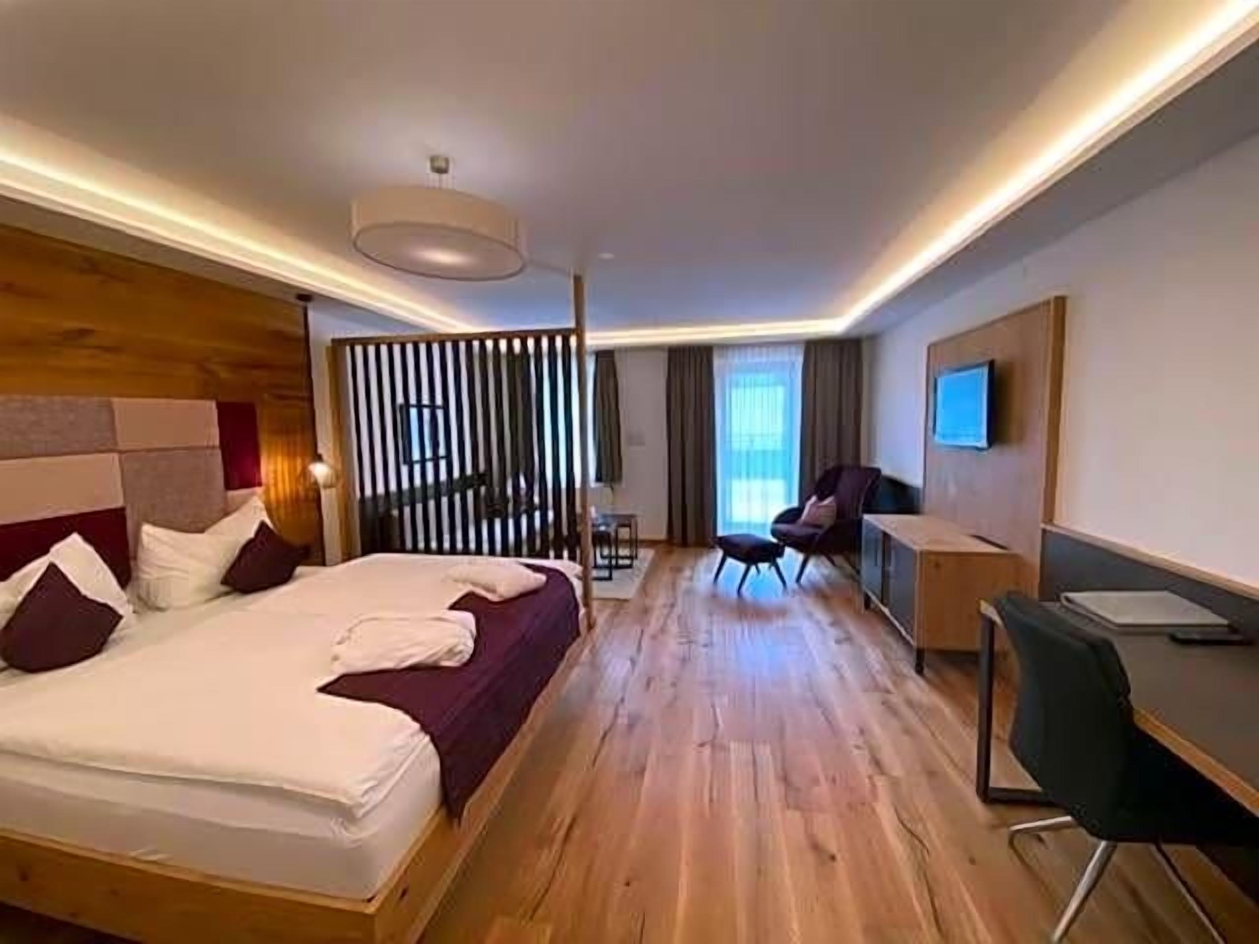 Habitación de hotel con una cama grande, un escritorio, una silla y un televisor.