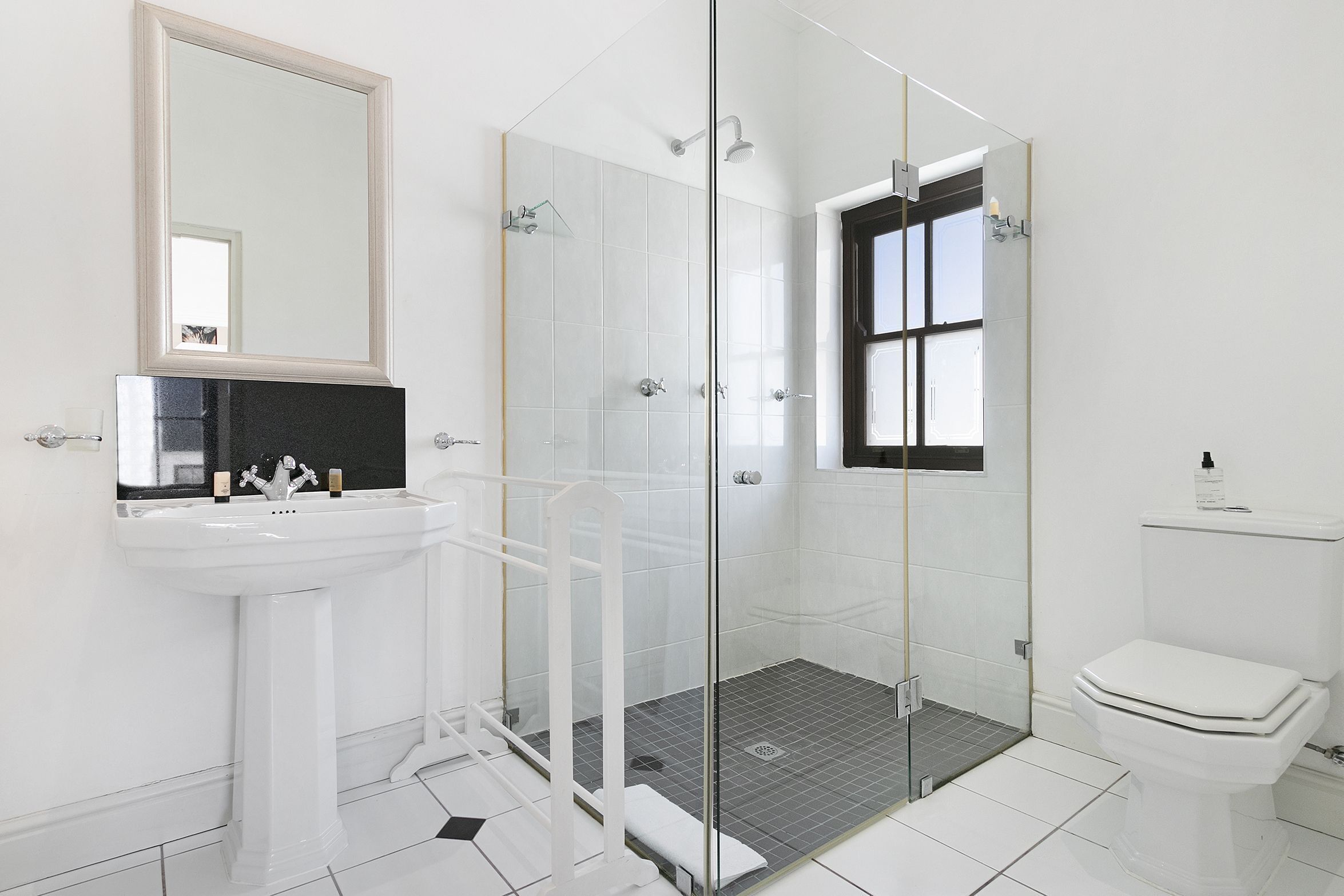 Une salle de bain moderne avec une douche à parois de verre, un lavabo sur colonne et des toilettes.