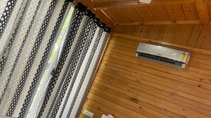 A wooden cabin room with a bed, a ceiling fan, and an air conditioning unit. - Okho Resort Kalka Panchkula (Kalka)
