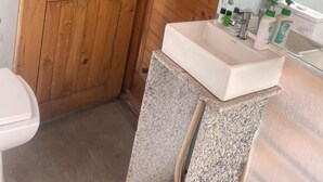 A bathroom with a wooden door, a white sink with a granite countertop, and a mirror above the sink. - Okho Resort Kalka Panchkula (Kalka)