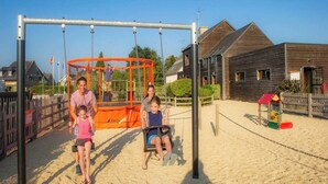 Un parque infantil con columpios y una zona de juegos cercada.