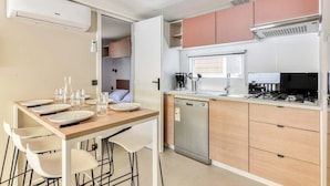 Una cocina moderna con comedor, electrodomésticos de acero inoxidable y armarios de madera clara.