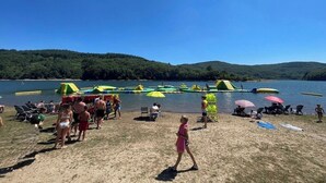 A lakeside beach with people, chairs, and inflatable rafts. - MAGNIFICENT Gîte for 4 to 10 people in NAGES 81/LAC DU LAOUZAS/HAUT LANGUEDOC (Nages)