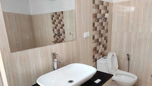 Un baño con un lavabo blanco, un inodoro y un espejo sobre el lavabo.