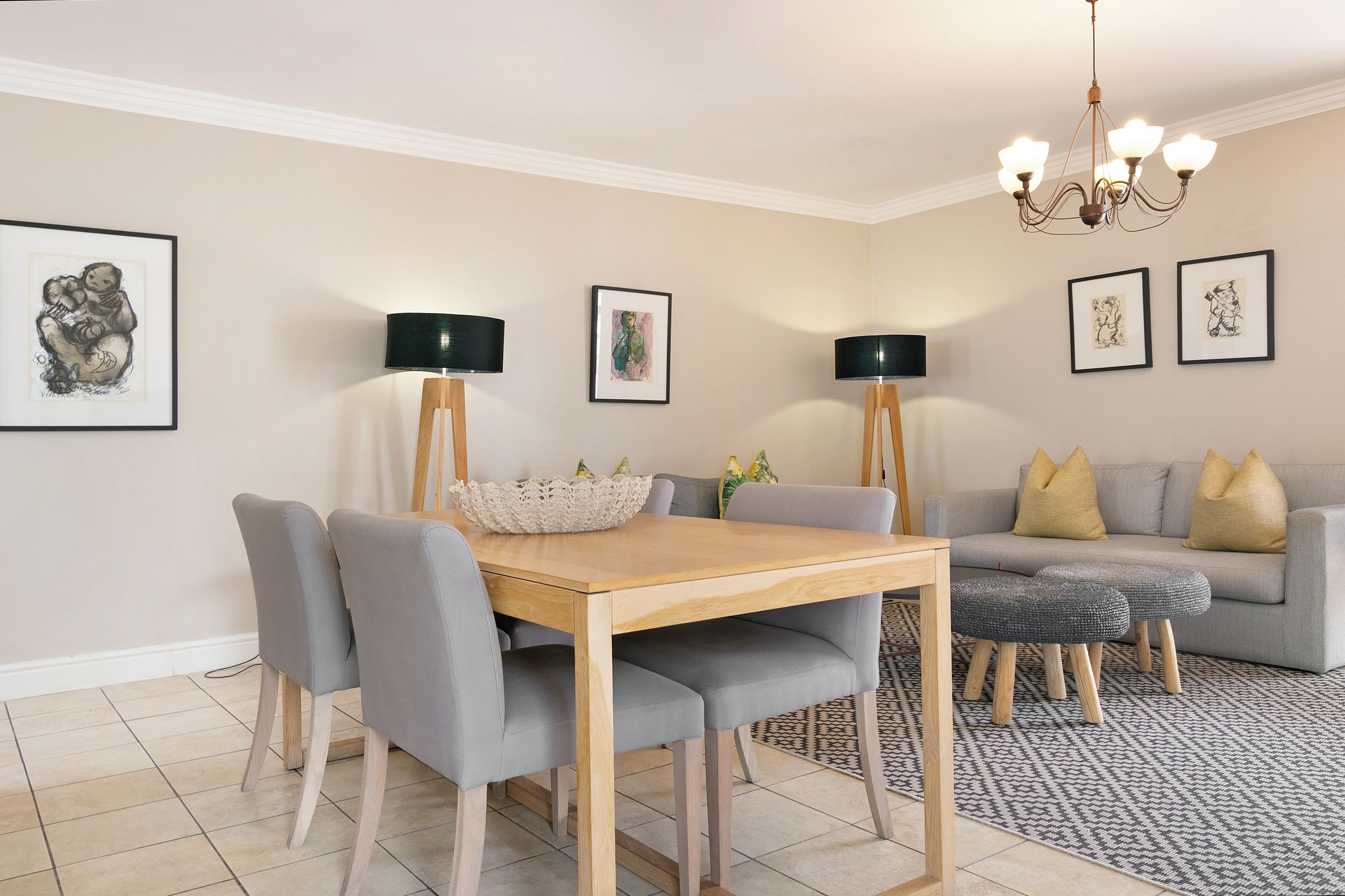 A dining area with a wooden table, grey upholstered chairs, and a black floor lamp.