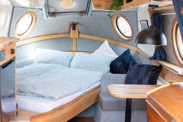 Un intérieur chaleureux avec un lit, une petite table et deux fenêtres.