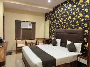 A hotel room with a bed, bedside table, and a window with blinds.