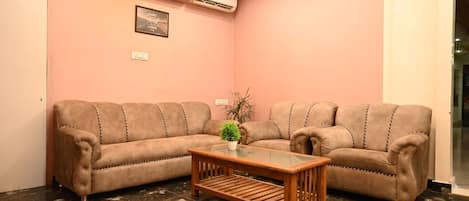 Una sala de estar con dos sofás, una mesa de centro y una planta en maceta.