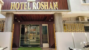 The entrance to Hotel Roshan with a sign above the door, a glass facade, and a metal gate to the right. - HOTEL ROSHAN (Varanasi)