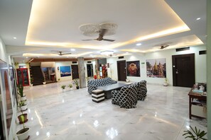 A spacious lobby with a central seating area, ceiling fans, and a large wall mural.